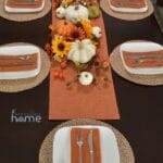 A simple tablescape for the fall season that is decorated with orange and white pumpkins and sunflowers.
