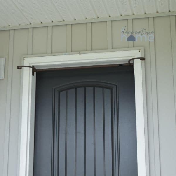 A front door with garland hanger at the top of the door frame.