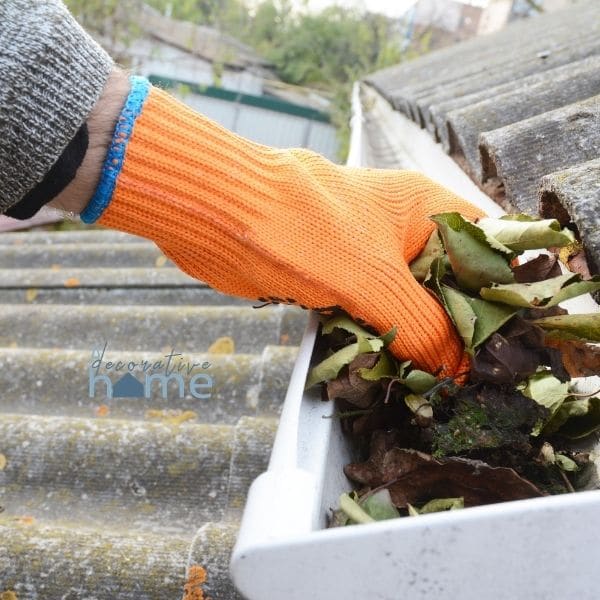 A gloved hand cleaning out the gutters to winterize your home.